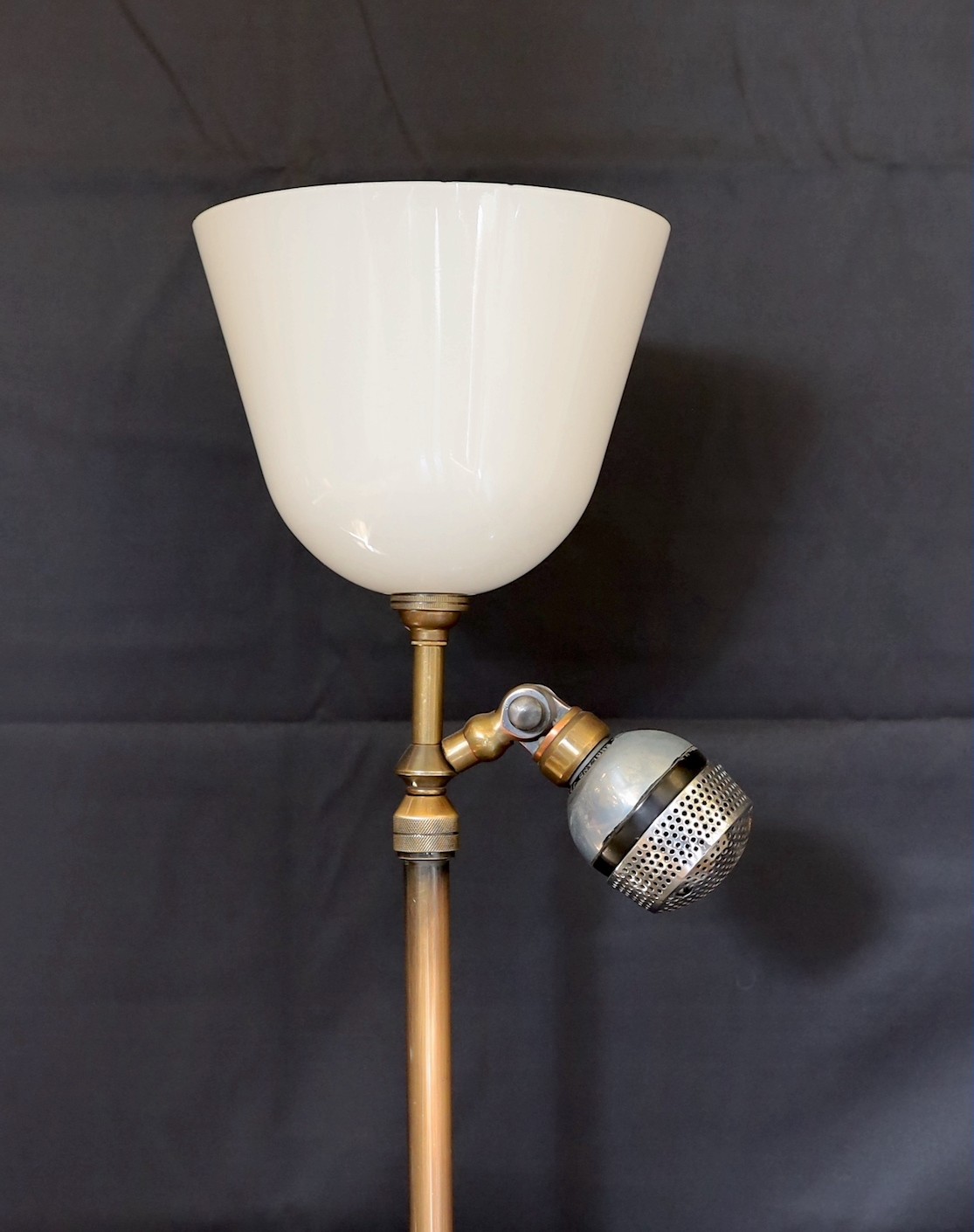 A 1920s BBC microphone converted to a table lamp, with loaded brass base and opaque white glass up lighter shade, height overall 66cm